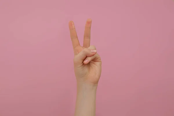 Жінка Показує Два Пальці Рожевому Фоні Крупним Планом — стокове фото