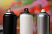 Plechovky různých graffiti sprej barvy na barevném pozadí, detailní záběr