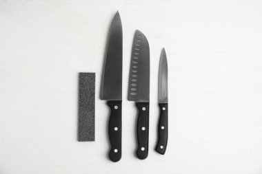 Keskinleştiren taş ve bıçak seti beyaz ahşap masa, düz yatıyordu.