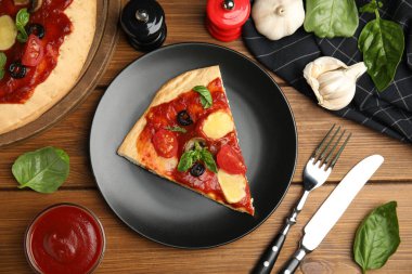 Lezzetli pita pizza dilimleri ve ahşap masa üzerindeki malzemeler.