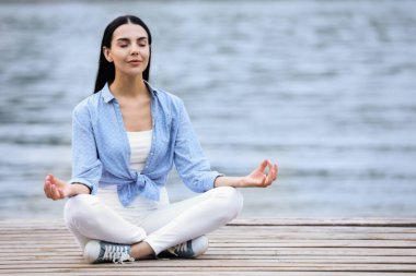 Nehir kenarında meditasyon yapan genç bir kadın. Metin için boşluk