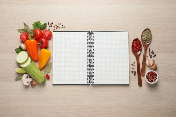 Blank recipe book and different ingredients on wooden table, flat lay. Space for text