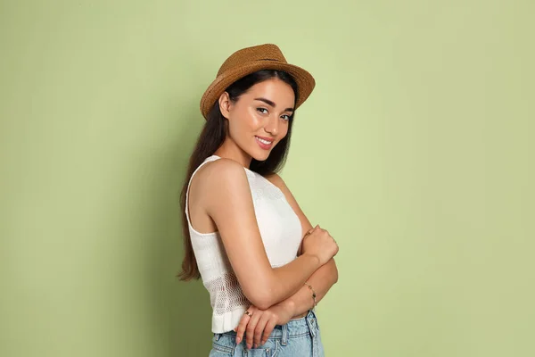 オリーブの背景に藁帽子をかぶった美しい若い女性 スタイリッシュなヘッドアドレス — ストック写真