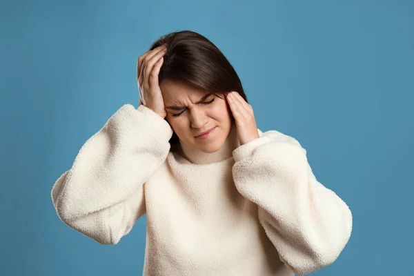 Açık Mavi Arka Planda Migren Ağrısı Çeken Genç Bir Kadın — Stok fotoğraf