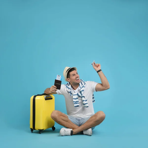 Mężczyzna Turysta Posiadający Paszport Biletem Zabawkowym Samolotem Pobliżu Walizki Turkusowym — Zdjęcie stockowe