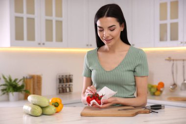 Mutfakta domatesleri kağıt havluyla silen kadın.