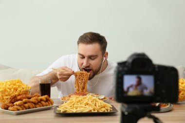 Yemek blogcusu, arka planda kamera karşısında yemek yeme şovu kaydediyor. Mukbang vlog