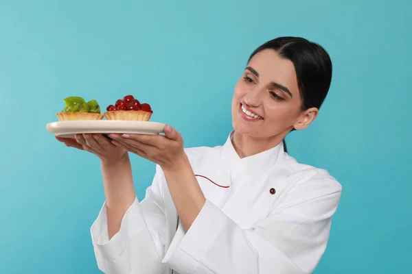 Felice Pasticcere Professionista Uniforme Con Deliziose Tortine Sfondo Azzurro — Foto Stock