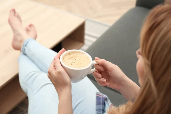 在家里沙发上喝杯咖啡放松的年轻女人 — 图库照片
