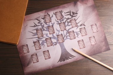Boş aile ağacı, tahta masa üzerinde defter ve kalem, düz uzanmış.