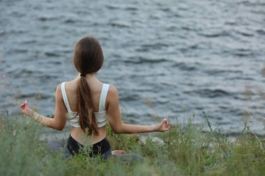 Genç bir kız nehrin kenarında meditasyon yapıyor. Metin için boşluk