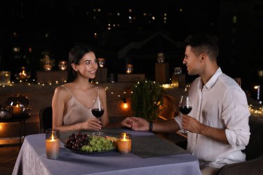 Geceleri terasta kırmızı şarap içen romantik bir çift.