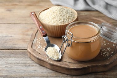 Lezzetli susam ezmesi kavanozu ve ahşap masada tohumlar.