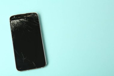 Açık mavi arkaplanda çatlak ekranı olan akıllı telefonun üst görünümü, metin için boşluk. Aygıt onarımı