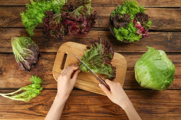 Vrouw Snijdende Rode Bladsla Aan Houten Tafel Bovenaanzicht — Stockfoto