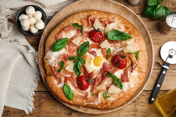 Pita pizza with prosciutto, pineapple, grilled tomatoes and egg on wooden table, flat lay