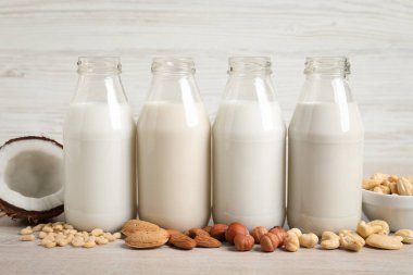 Beyaz masada cam şişelerde farklı fındıklı sütler.