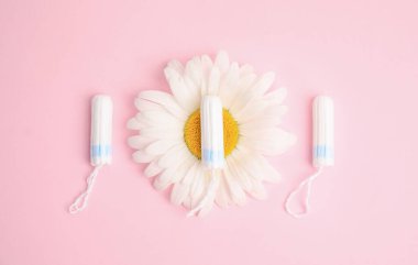 Açık pembe arkaplanda tamponlar ve papatya çayı, düz bir zemin