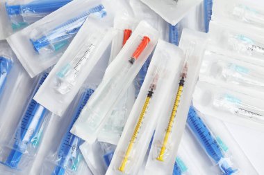 Beyaz zemin üzerinde iğneler olan tek kullanımlık şırıngalar, üst görünüm