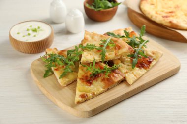 Beyaz ahşap masada servis edilen peynirli lezzetli khachapuri.