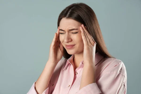 Gri Arka Planda Migren Ağrısı Çeken Genç Bir Kadın — Stok fotoğraf