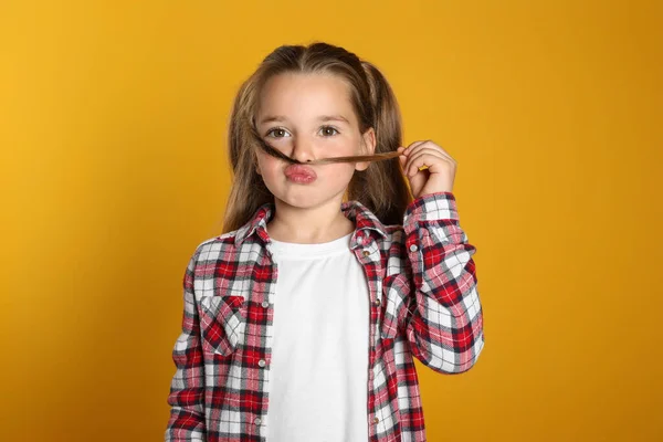 Zabawna Dziewczynka Robi Sztuczne Wąsy Włosami Żółtym Tle — Zdjęcie stockowe