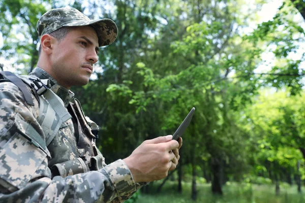森の中でタブレットを使用してリュックを持つ兵士 — ストック写真
