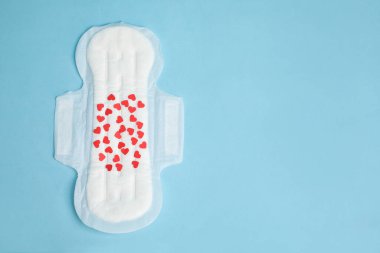 Açık mavi arka planda konfetisi olan regl yastığı, üst manzara. Metin için boşluk