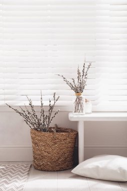 Pussy willow tree branches and pillow near window in room