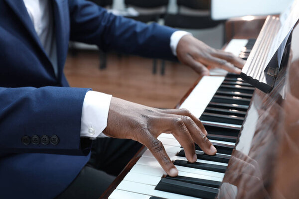 Афроамериканец играет на пианино в помещении, крупным планом. Талантливый музыкант