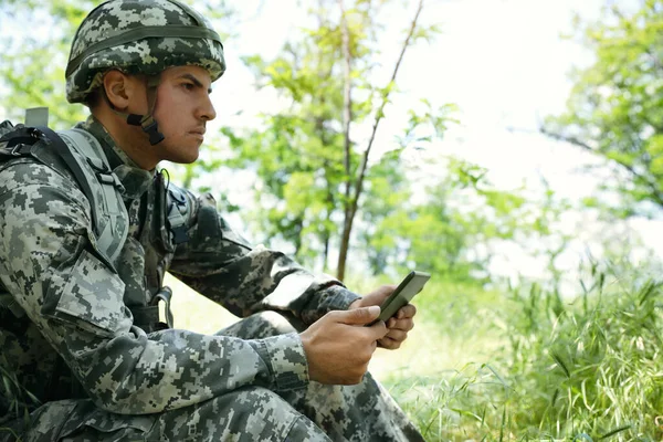 森の中でタブレットを使用してリュックを持つ兵士 — ストック写真