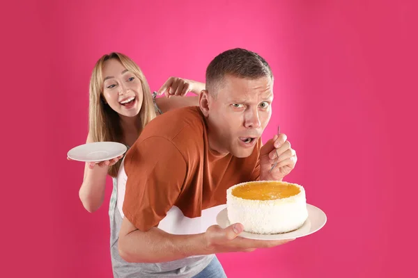 Gieriger Mann Versteckt Leckeren Kuchen Vor Frau Auf Rosa Hintergrund — Stockfoto