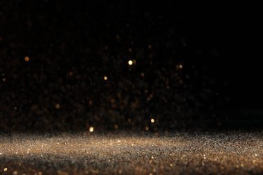 Siyah arkaplana dökülen parlak altın parıltı. Bokeh etkisi
