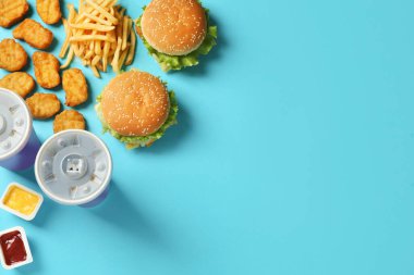 Açık mavi arka planda lezzetli fast food menüsü olan düz kompozisyon. Metin için boşluk