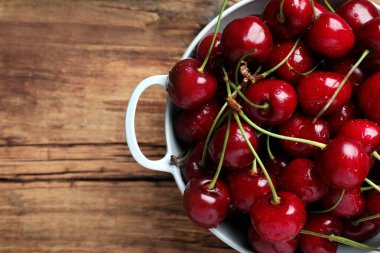 Ahşap masadaki süzgeçte ıslak kırmızı kirazlar, üst manzara. Metin için boşluk