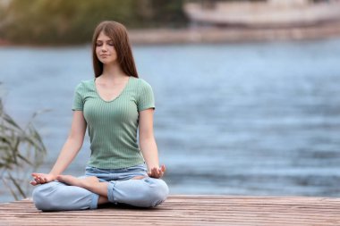 Nehir kenarında meditasyon yapan genç bir kız. Metin için boşluk
