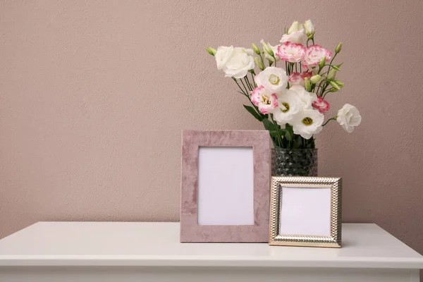 空の写真フレームとピンクの壁の近くの白いテーブルの上の美しい花束 テキストのためのスペース — ストック写真