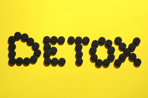 単語黄色の背景に活性炭錠剤で作られたデトックス フラットレイアウト 強壮剤 — ストック写真