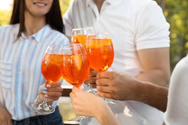 Arkadaşlar bardakları tıkırdatıyor Aperol spritz kokteylleri dışarıda, yakın plan