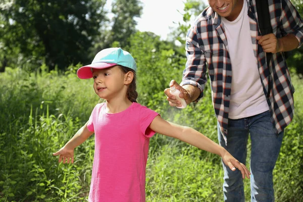 在大自然中远足时 父亲在他的小女儿的胳膊上喷洒驱蚊剂 — 图库照片