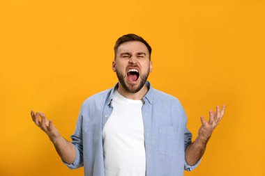 Sarı arka plandaki kızgın genç adam. Nefret konsepti