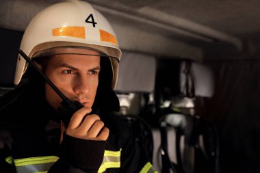 İtfaiyeci itfaiye aracında taşınabilir radyo kullanıyor, mesaj için yer var.