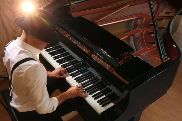 Man playing piano indoors, above view. Talented musician