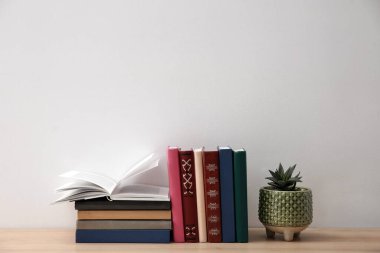 Beyaz duvarın yanındaki ahşap masada kitap ve bitki koleksiyonu. Metin için boşluk