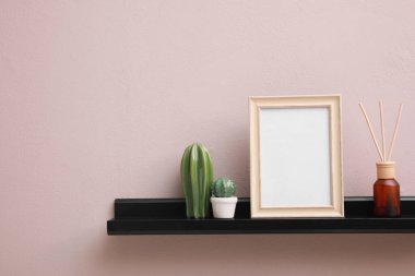 Boş fotoğraf çerçevesi, kaktüs figürleri ve hava sazlığı spreyi pembe duvarın yanında, metin için yer var.