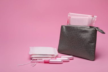 Gümüş çanta, adet pedleri ve pembe arka planda tamponlar.