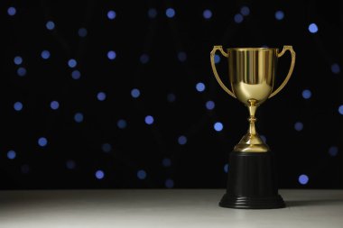 Beyaz masadaki altın kupa bulanık ışıklara karşı, metin için yer