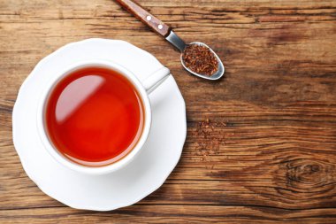 Taze demlenmiş rooibos çayı, kuru yapraklar ve tahta masada kaşık, düz uzanma. Metin için boşluk
