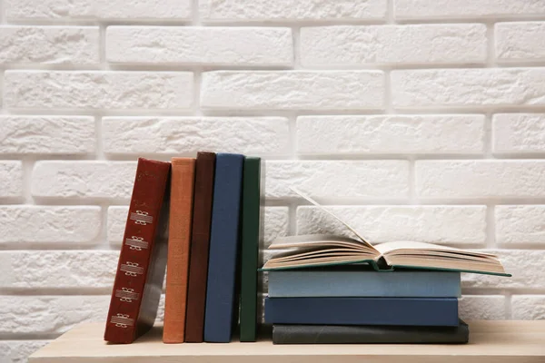 白砖墙附近木制桌子上的不同书籍 — 图库照片