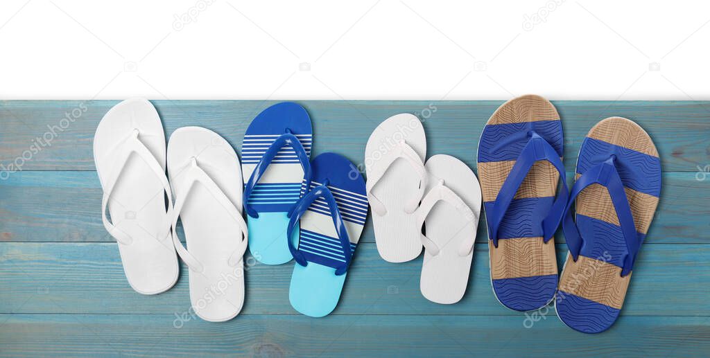Different stylish flip flops on turquoise wooden table against white background, top view